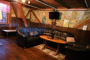 a living room with a leather couch and a table at Forest Cabin Ponikve in Čajniče