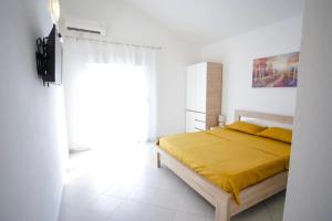 a bedroom with a bed with a yellow blanket at Apartments Sofia in Sutomore