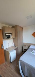 a hotel room with a bed and a small kitchen at Estúdio Paris Lagoa Santa in Lagoa Santa