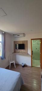 a bedroom with a bed and a shower and a window at Estúdio Paris Lagoa Santa in Lagoa Santa