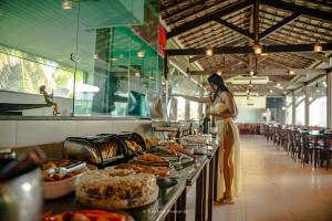 a woman standing in a buffet line with food at Pousada Oásis Tropical in Porto De Galinhas