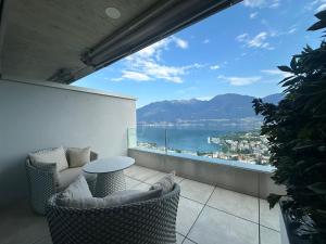 a balcony with a table and chairs and a view of the water at Room Casa Jessika in Orselina
