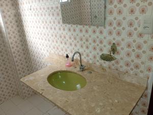 ein Badezimmer mit einem grünen Waschbecken und einem Spiegel in der Unterkunft Apartamento Gonzaga Santos in Santos + 82 Fotos