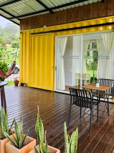 a yellow house with a table and chairs on a deck at Kolibri Containers Boyacá in Guayatá