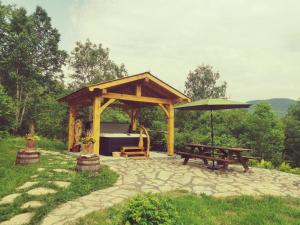 a wooden gazebo with a picnic table and an umbrella at Gîte de l'herboriste spa et vue sur la fjord in Sainte-Rose-du-Nord