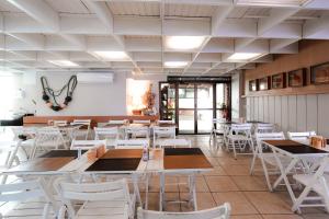 a dining room with white tables and white chairs at Carppa Hotel in Fortaleza