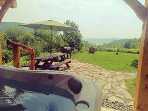 a hot tub with an umbrella and a picnic table at Gîte de l'herboriste spa et vue sur la fjord in Sainte-Rose-du-Nord