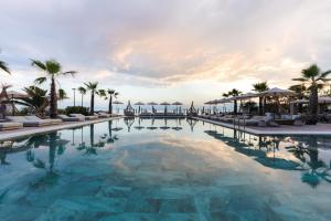 a large swimming pool with palm trees and umbrellas at Medite Kassandra Resort in Nea Moudania +32 photos