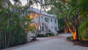 a white house with palm trees and a driveway at Paradise Inn - Adult Exclusive in Key West