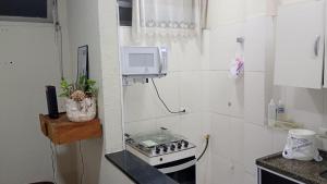 a kitchen with a stove and a microwave on the wall at Apto Gonzaga a 20m da praia -Ar Split & Pet Friendly in Santos +55 photos