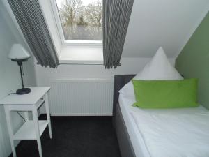 a bedroom with a bed with a green pillow and a window at Landhaus Elbeflair bei Dömitz in Lenzerwische