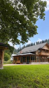 a large wooden building in a park with green grass at Cabana Pârâul Lupilor in Răchitiş