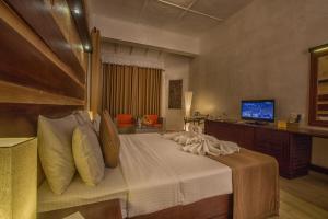 a bedroom with a large bed and a television at Avenra Beach Hikkaduwa in Hikkaduwa