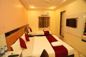 a hotel room with two beds and a television at Hotel Rinza Residency in Mumbai