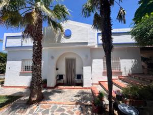 a white house with palm trees in front of it at Alojamiento Colinas in Monachil