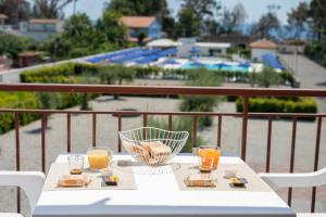 a table with three glasses of orange juice on a balcony at Teresan Homestay in Mascali