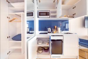 a kitchen with white shelves and a microwave at Panorama Central Batumi in Batumi