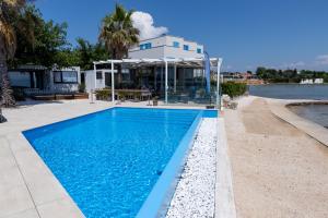 a swimming pool in front of a house at Arcadia - Beach villa n.1 in Privlaka