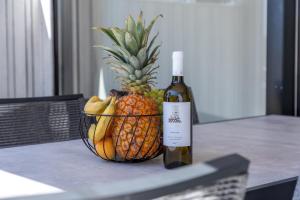 a basket of fruit with a bottle of wine and a pineapple at Arcadia - Beach villa n.1 in Privlaka