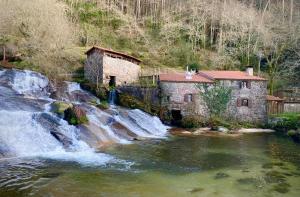 a waterfall next to a building next to a river at Casita San Simon in Bayón