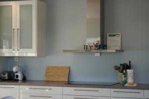 a kitchen with white cabinets and a blue wall at LofotenApartmentOne in Stamsund +69 photos