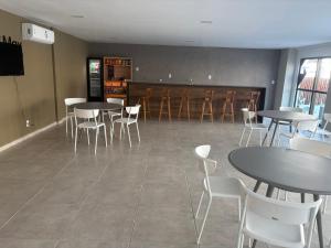 a dining room with tables and white chairs at Flat na Praia dos Carneiros - Resort Max Carneiros Suítes in Tamandaré