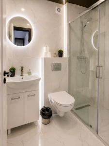 a white bathroom with a toilet and a shower at Powidz Comfort Suites in Powidz