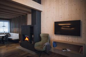 a living room with a fireplace and a chair and a television at Kessler's Mountain Lodge in Natz-Schabs