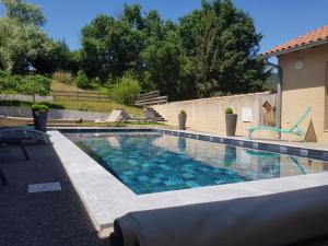 a swimming pool with blue water in a yard at Hôtel Les Rives D'Allier in Mazeyrat-d'Allier