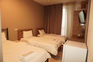 a hotel room with two beds and a television at Hotel PM Palace in Nizhnyaya Alekseyevka