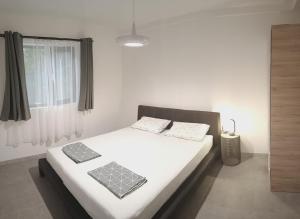 a bedroom with a bed with white sheets and a window at Apartments Spasoje 2 in Kotor