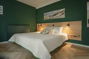 a bedroom with a large bed with green walls at DuinHotel Texel in De Koog