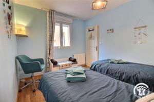 a bedroom with two beds and a green chair at La croix au roi in Lamballe Armor