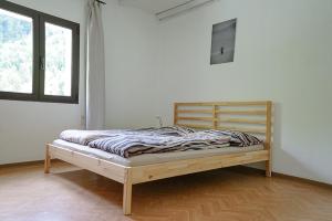 a bed in a white room with a wooden frame at Ristorante Locanda Zott in Valle Onsernone in Vergeletto
