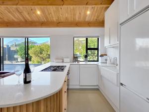 a white kitchen with a bottle of wine on a counter at Lily of the Valley - Higgovale in Cape Town