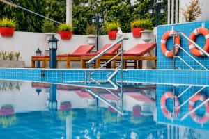 a swimming pool with red chairs and a blue tile wall at Christella Hotel Laemchabang in Si Racha