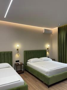 two beds in a room with green accents at Olivium Rooms in Vlorë