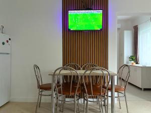 a dining room table with chairs and a television on a wall at Casa Alba - Tasnad in Tăşnad