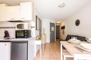 a kitchen and living room with a table and a microwave at Valras-Loc - T2 Piscine Terrasse in Valras-Plage