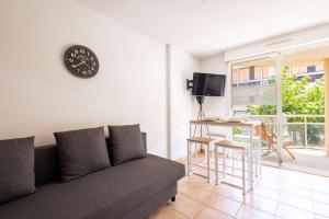 a living room with a couch and a clock on the wall at Valras-Loc - T2 Piscine Terrasse in Valras-Plage +4 photos