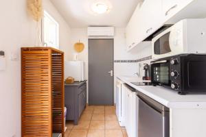 a kitchen with white counters and a black microwave at Valras-Loc - T2 Piscine Terrasse in Valras-Plage