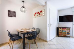 a dining room with a table and chairs and a tv at Valras-Loc Maison T3 in Valras-Plage
