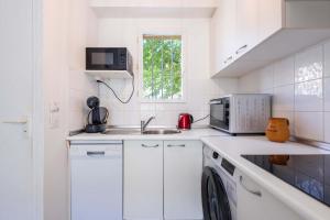 a white kitchen with a sink and a microwave at Valras-Loc Maison T3 in Valras-Plage