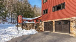 a red house with a garage and a sign in the snow at Luxe Vermont Duplex in Stowe +21 photos