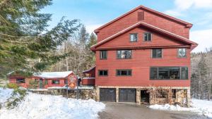 a red house with a garage in the snow at Luxe Vermont Duplex in Stowe
