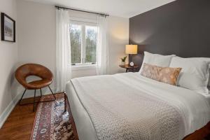 a bedroom with a bed and a chair and a window at Luxe Vermont Duplex in Stowe