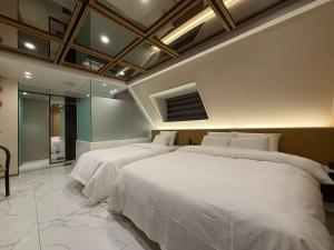a bedroom with two beds with white sheets at 잠실 라운지 호텔 in Seoul