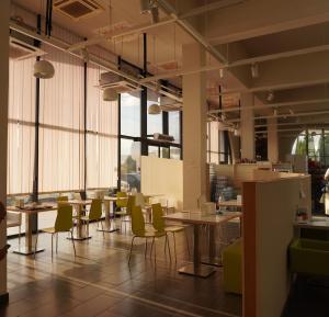 a room with tables and chairs and windows at Hotel PM Palace in Nizhnyaya Alekseyevka