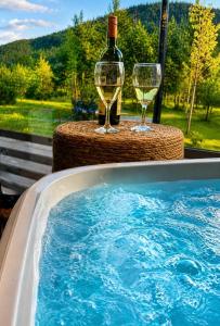a tub with two wine glasses and a bottle of wine at Star Villas Žabljak in Borje