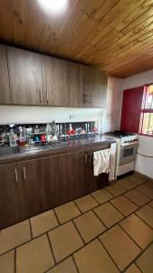 a kitchen with wooden cabinets and a stove top oven at Valle Sereno, Hospedaje rural cerca del Salto del Buey in Abejorral
